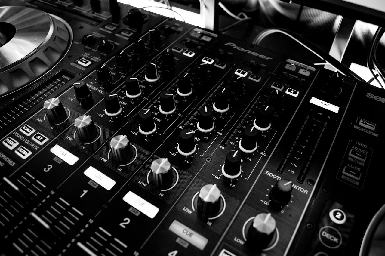 Black and white close-up of a DJs audio mixing console with knobs and controls.